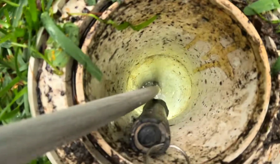 Close-up camera view into a Spokane sewer cleanout showing mineral and grease scale coating the pipe walls, the kind of buildup hydro jetting removes